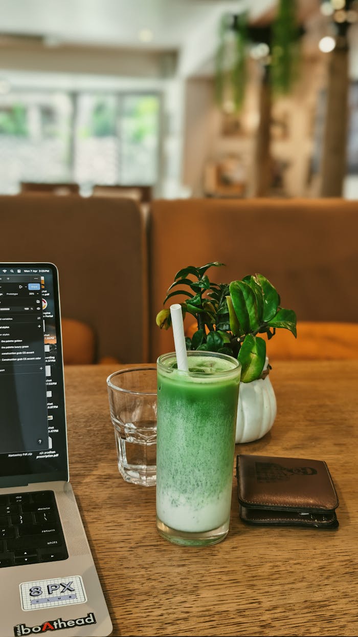 A cozy cafe setup featuring a laptop, matcha latte, and greenery, ideal for freelancers.
